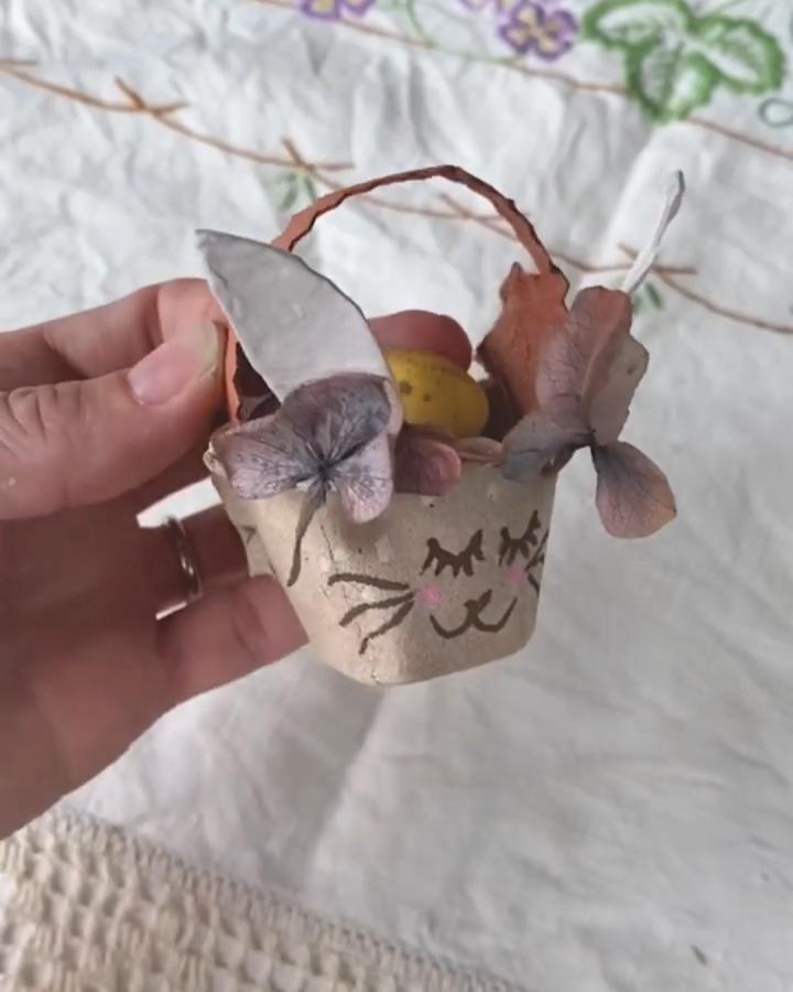 brown egg carton bunny basket decorated with dried hydrangea flowers from @_dimity_ held in hand on embroidered cloth background