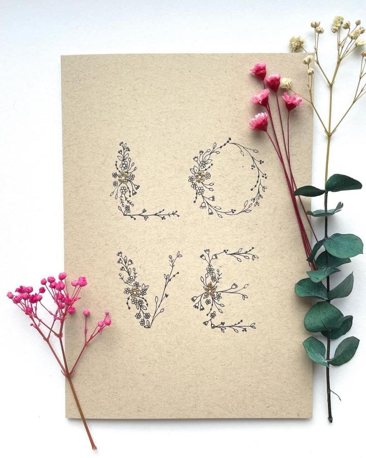 kraft paper card with black floral lettering and pink dried flowers from @ali.embers.paper delicate handmade valentines card ideas with natural elements