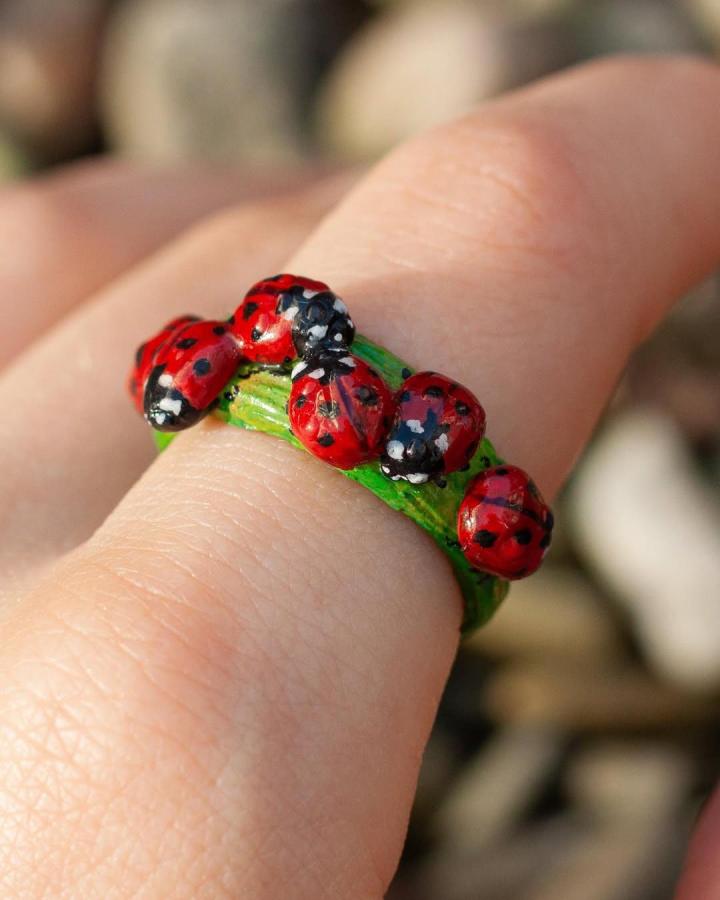 Bright red and black ladybug clay ring with green leaf band from @ona.clay.ring showing ladybug crafts for adults.