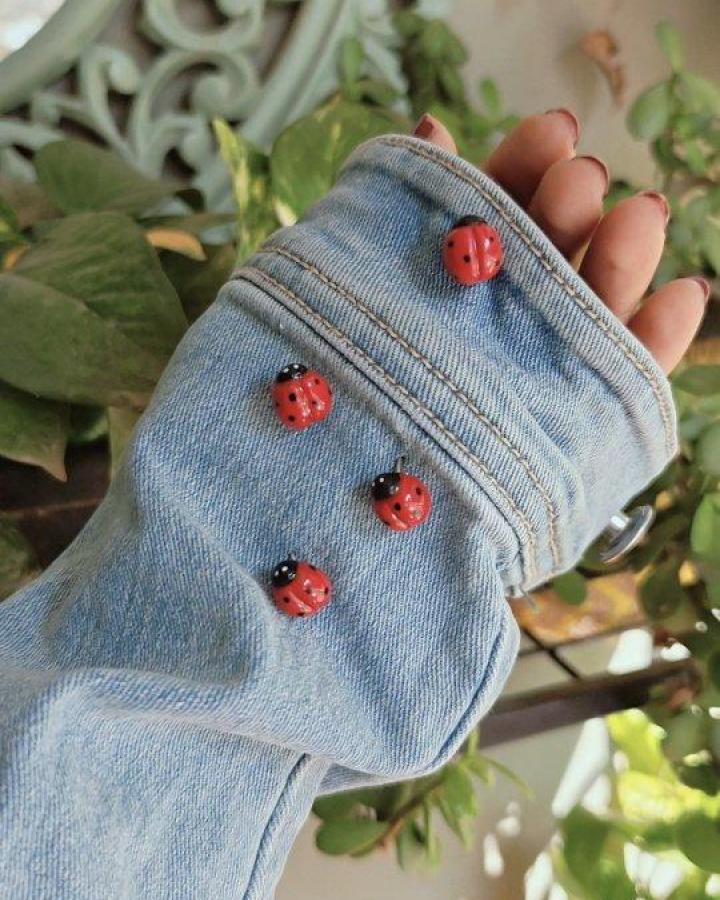 Bright red ladybug pins on light blue denim jacket sleeve from @thebookishpandora. Playful ladybug crafts for adults with a casual vibe.