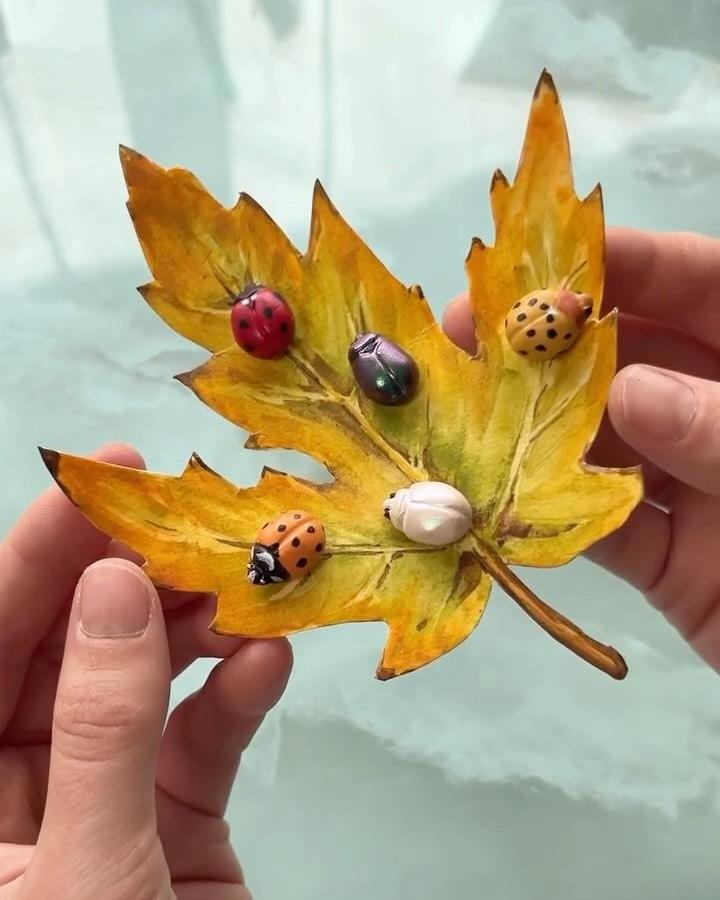 Yellow and brown autumn leaf with colorful miniature ladybug crafts for adults from @ystreetstudio. Hands holding detailed leaf art.