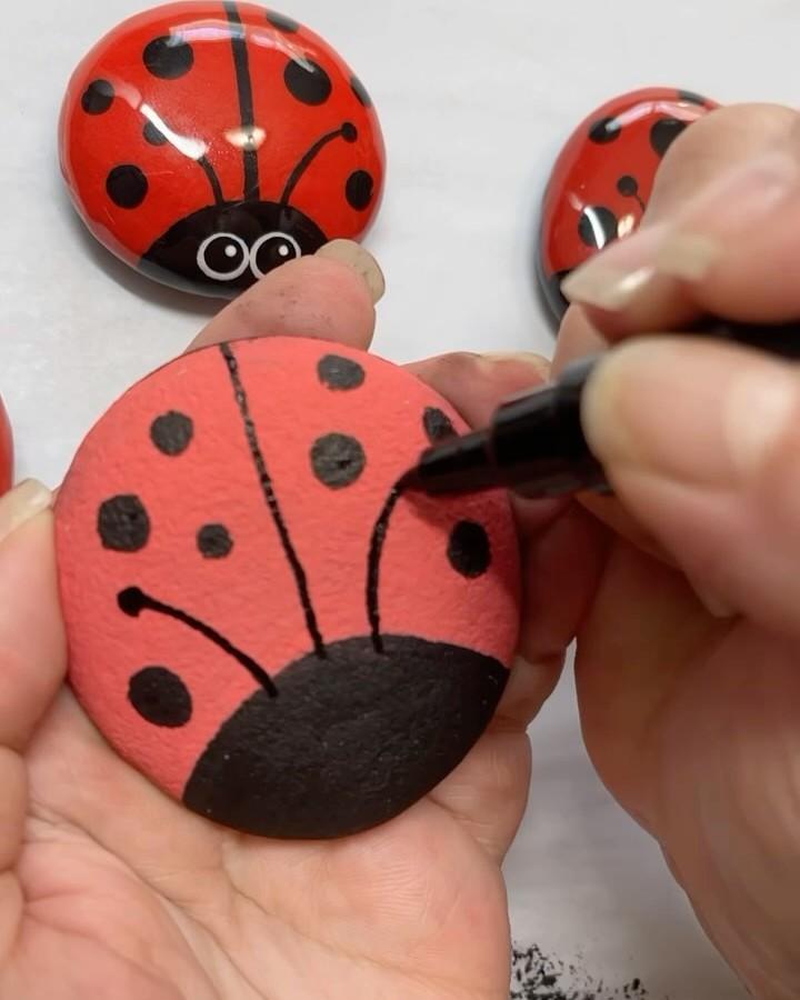 Bright red and black hand-painted ladybug stones from @lorybugrocks crafted with bold spot details and marker outlines.
