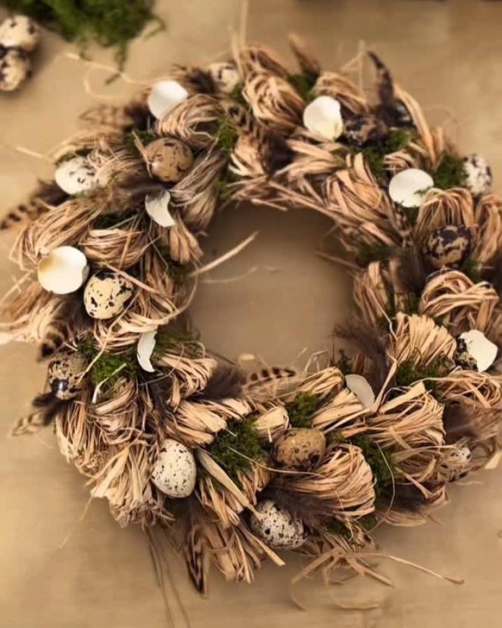Natural raffia and feather wreath with speckled eggs and moss from @canea_ostrava showing spring wreath ideas with rustic materials.