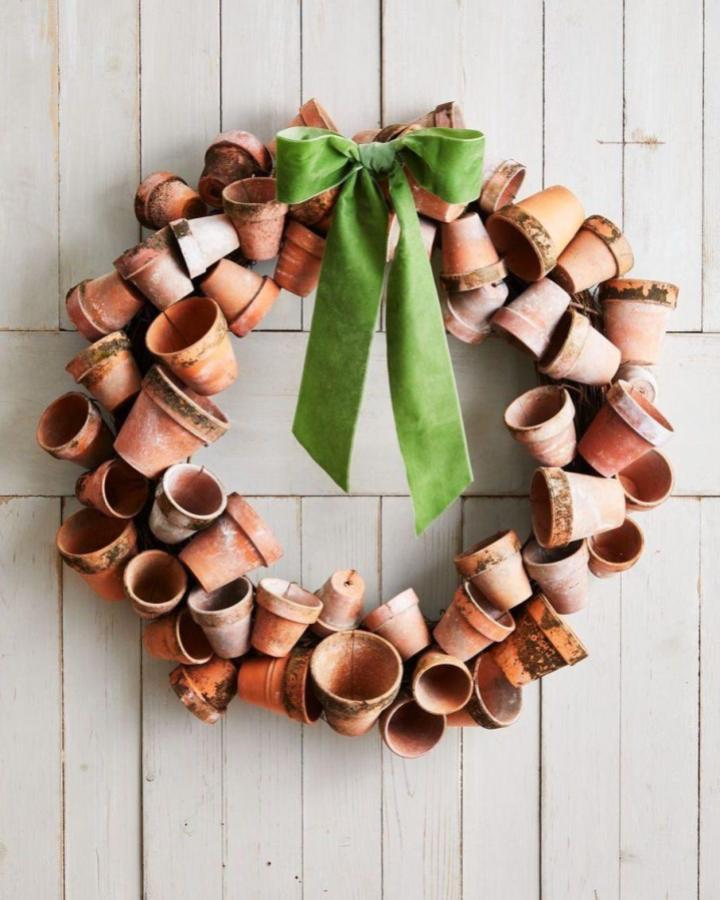 Rustic terracotta pot wreath with green velvet bow from @alzysopp featured on @countrylivingmag. Unique spring wreath ideas for home decor.