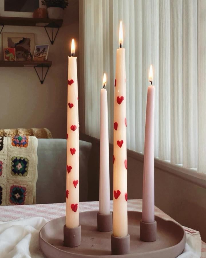 White and pink taper candles with red hand-painted hearts on a beige tray for valentines crafts for adults.