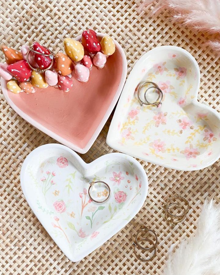 pink and white hand painted ceramic heart dishes with floral design and clay buds from @amandaescoe valentines crafts for adults jewelry holders on woven surface