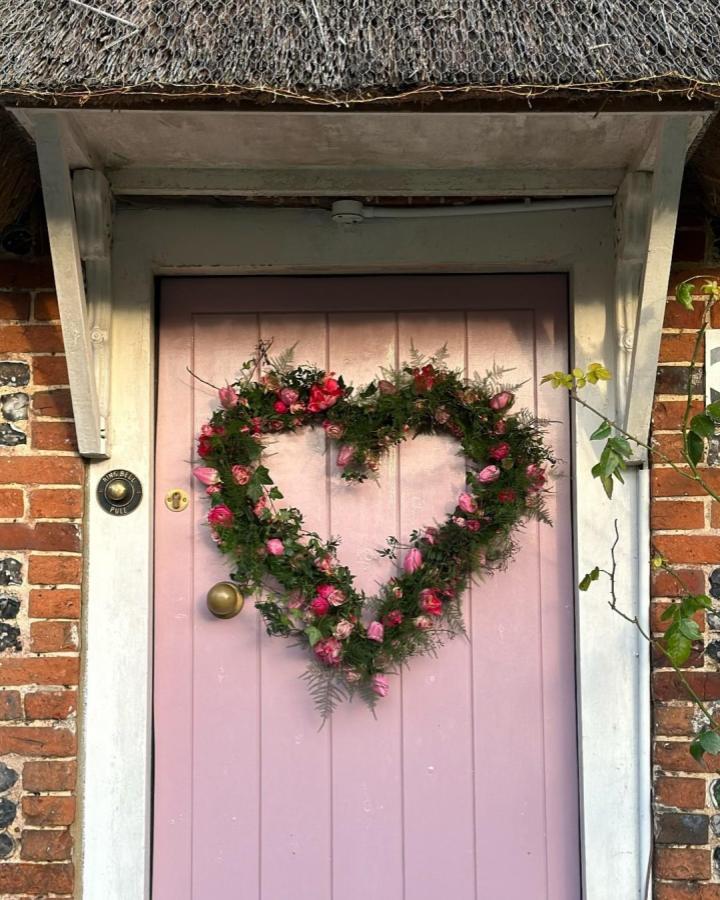 Pink and red floral heart-shaped wreath on a lavender door from @claudiaandb perfect for valentines crafts for adults.