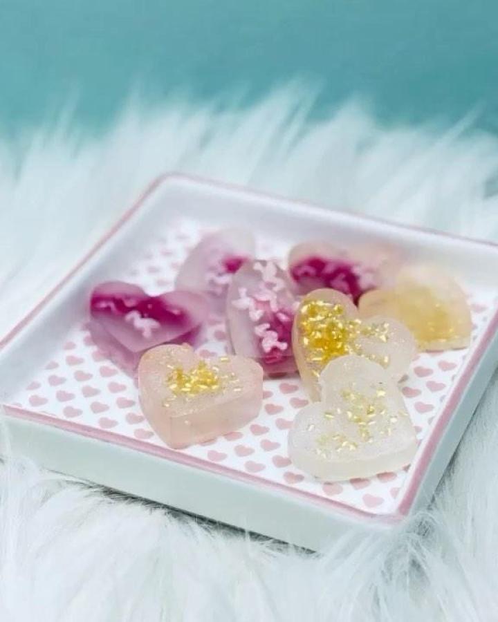 pink and purple glittery heart resin valentines crafts for adults on a white heart patterned tray from @sweetup.yourlife showing delicate handmade details