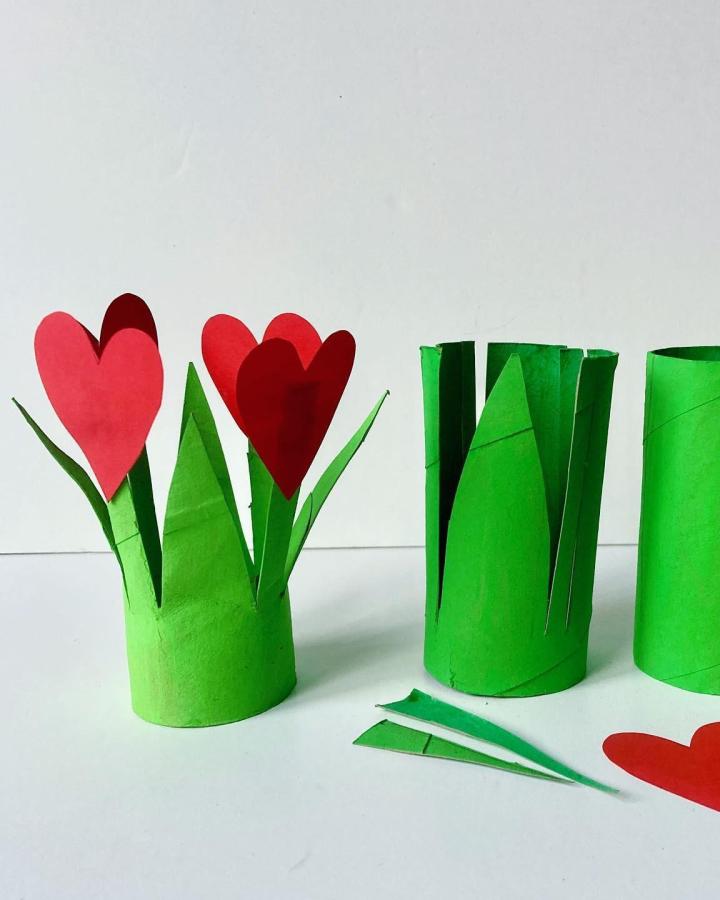 Green painted toilet paper rolls transformed into flower stems with red paper heart petals valentines crafts for kids from @jumbletree. Simple recycled craft idea.