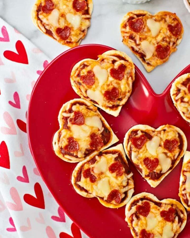 heart shaped mini pizzas on a red plate valentines crafts for kids from Hello Yummy playful edible craft with pepperoni and cheese hearts