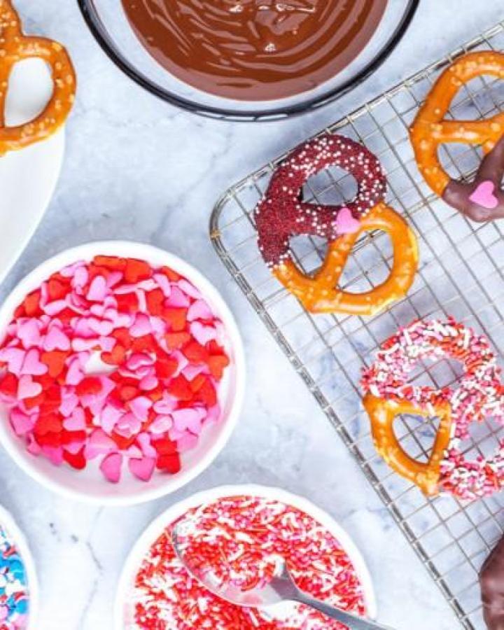 Pink and red heart sprinkle dipped pretzels on cooling rack from The PKP Way valentines crafts for kids chocolate and pretzel snack.