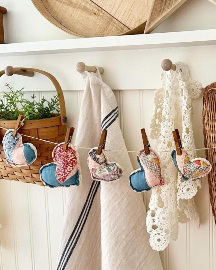 soft patchwork fabric hearts hanging on twine with wooden clips valentines heart garland ideas from @theoldehomesteadmarket rustic cozy kitchen decor
