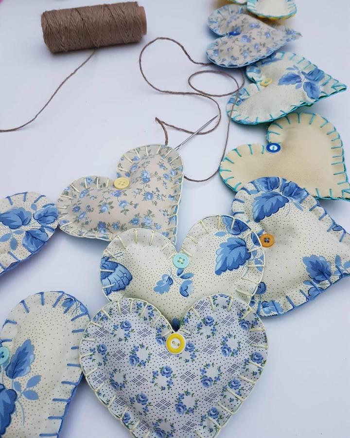 Soft blue floral fabric hearts with blanket stitch and buttons on twine string from @hopstitchbunt handcrafted valentines heart garland ideas.