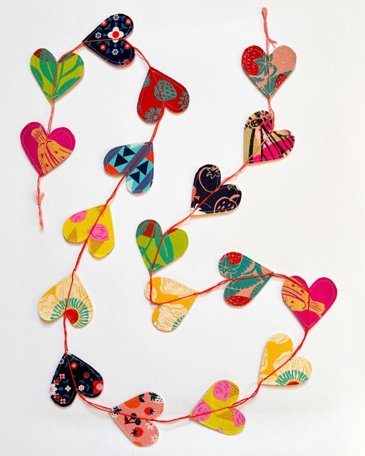 Colorful patterned paper heart garland from @andriafaye with sewn red thread holding hearts together.