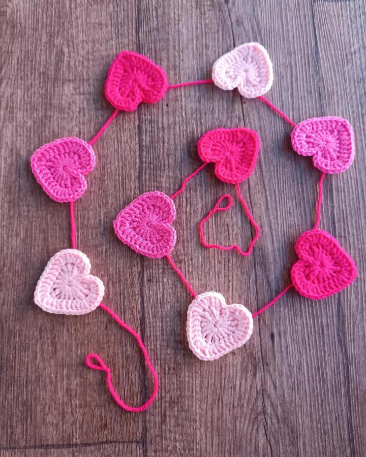 pink and red crochet heart garland on wood surface valentines heart garland ideas from @daisylady.tr handcrafted yarn decoration