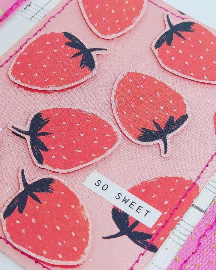 Red strawberry paper cutouts with dark green tops on light pink fabric background from @thecurioustrinket. Valentines paper craft ideas with stitched accents and playful text.
