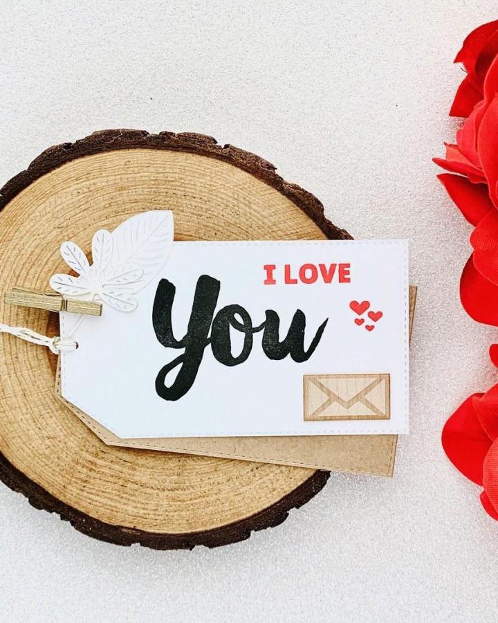 White and kraft paper valentines gift tag with black and red lettering on wood slice from @hildaluevano. Simple charming valentines paper craft ideas.