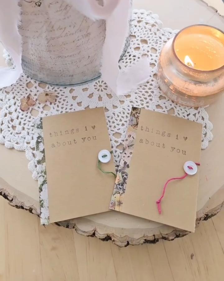 kraft paper mini books with buttons and yarn ties valentines paper craft ideas on wooden surface with candle and lace doily from @handmadeonpoplar