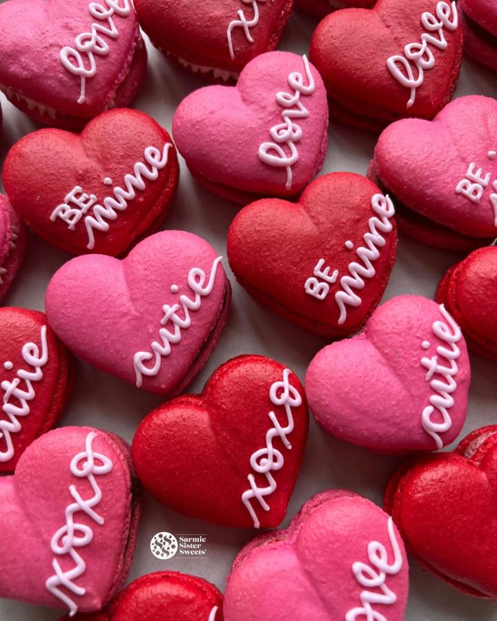 Pink and red heart-shaped macarons from @sarmiesistersweets decorated with sweet handwritten messages perfect for Valentines treat ideas