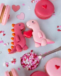 Pink and red dinosaur macarons with heart detail and sprinkles from @petite.meringue for valentines treat ideas.
