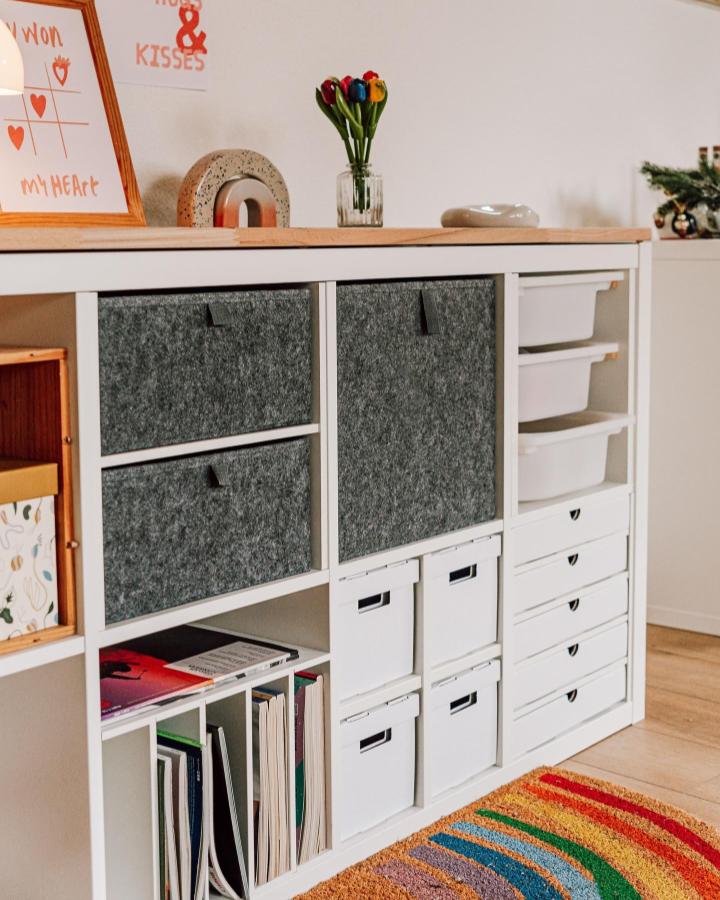 grey felt and white plastic modular ikea kallax inserts storage unit from @kallaxshop.de. cozy, practical living room organizer with colorful rug