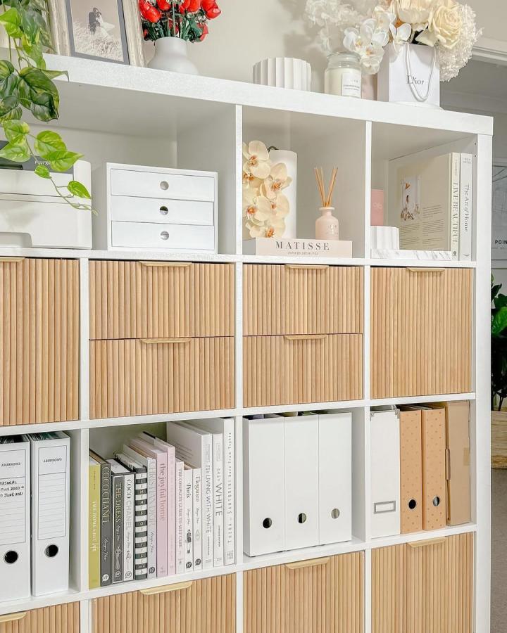 white frame shelving unit with natural rattan texture woven ikea kallax inserts from @stylingmyinterior neatly organizing home office storage