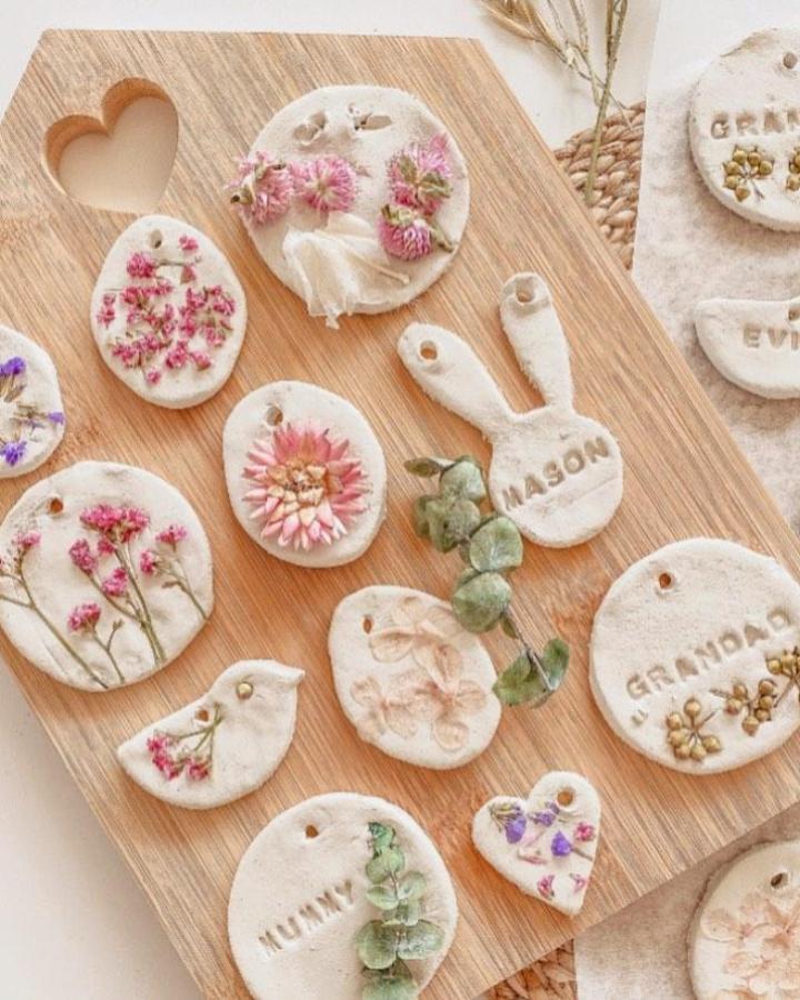 Soft white air dry clay Easter tags with pressed flowers from @efi_little_things. Personalized and delicate handmade decorations.