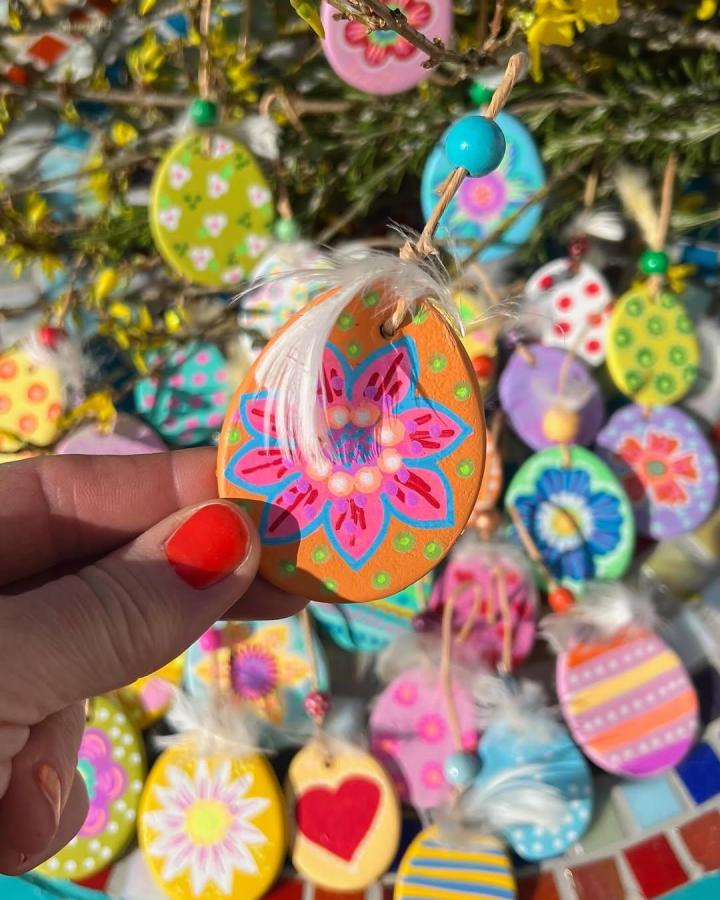 Orange floral clay egg ornament with feather and twine from @aliciauraa. Bright spring easter clay craft ideas decoration.