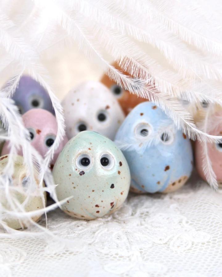 Speckled pastel clay eggs with playful eyes and soft feathers for easter clay craft ideas from @amakersstudio.