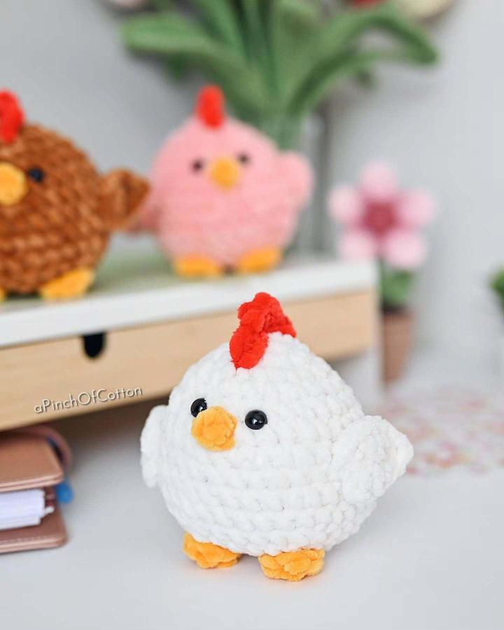 White chunky plush crochet chick with orange beak and feet and red comb from @bomuldskys Easter crochet ideas on desk.