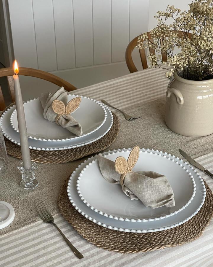 Neutral woven placemats and linen napkins with crochet bunny ears from @_katiepeakehome create warm easter table decor ideas.