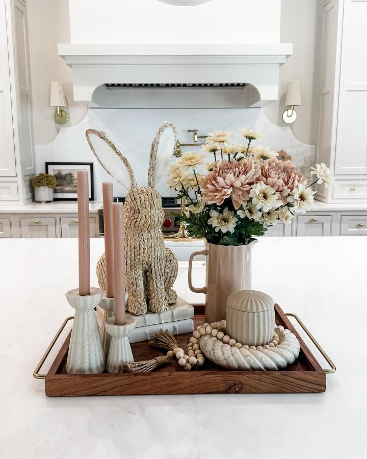 Woven straw bunny and pastel flower arrangement with pink candles on wooden tray from @ashleymariesavage for easter table decor ideas.