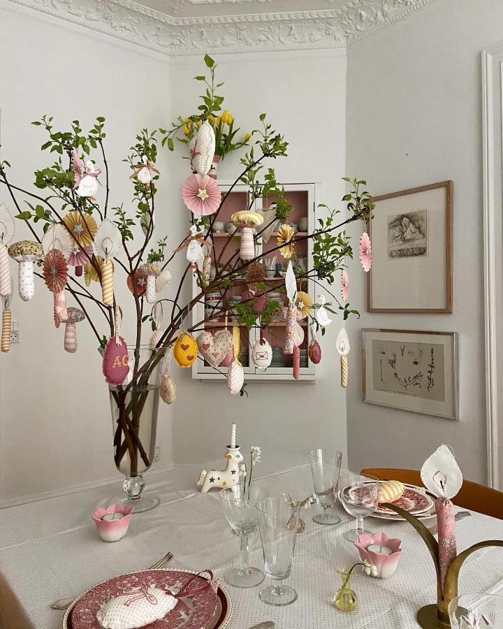 Pastel fabric Easter egg ornaments hanging on leafy branches from @papirkalas creating charming easter table decor ideas with soft, cozy textures.