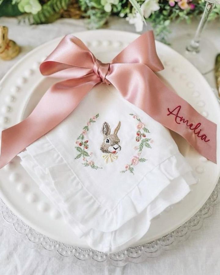 Soft pink satin ribbon tied on embroidered bunny napkin easter table decor ideas from @theembroiderednapkincompany.