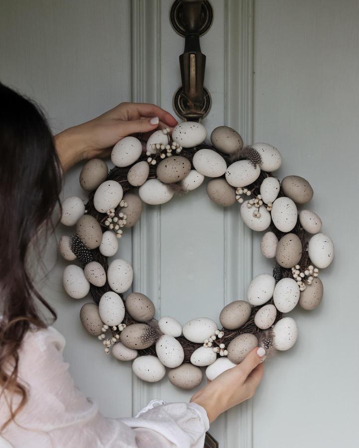 Neutral speckled egg Easter wreath with berries and feathers from @the_suffolk_nest on a pale door.