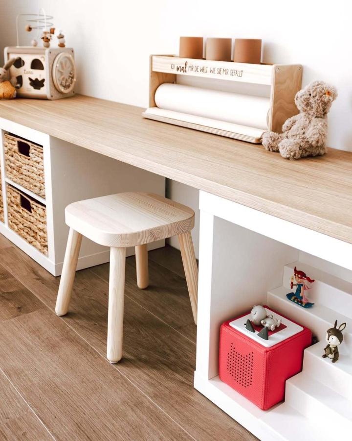Light natural wood and white ikea kallax desk hacks & ideas with woven baskets and wooden stool from @kallaxshop.de in a cozy kids workspace.