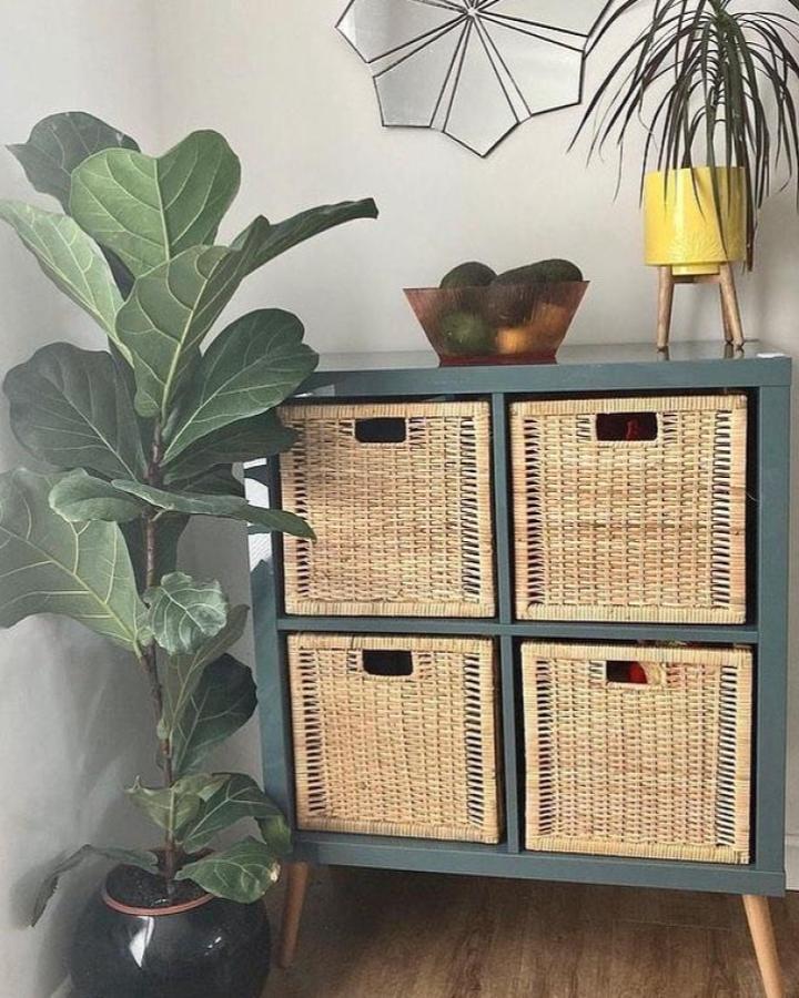 Teal painted Ikea Kallax with natural woven basket drawers and wooden legs in cozy living space from @shiftabrick. ikea kallax dresser hacks & ideas.