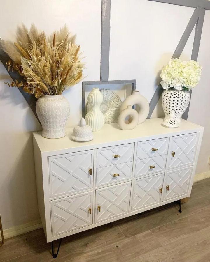 White textured Ikea Kallax dresser hack with brass knobs and hairpin legs styled by @fourcornersinteriors with decorative vases and dried florals.
