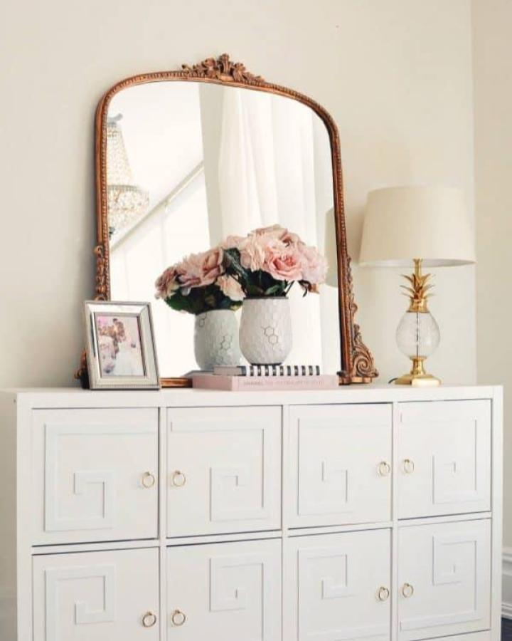 White Greek key pattern doors on dresser inspired by ikea kallax dresser hacks & ideas from The Pink Dream with vintage mirror and soft floral accents.