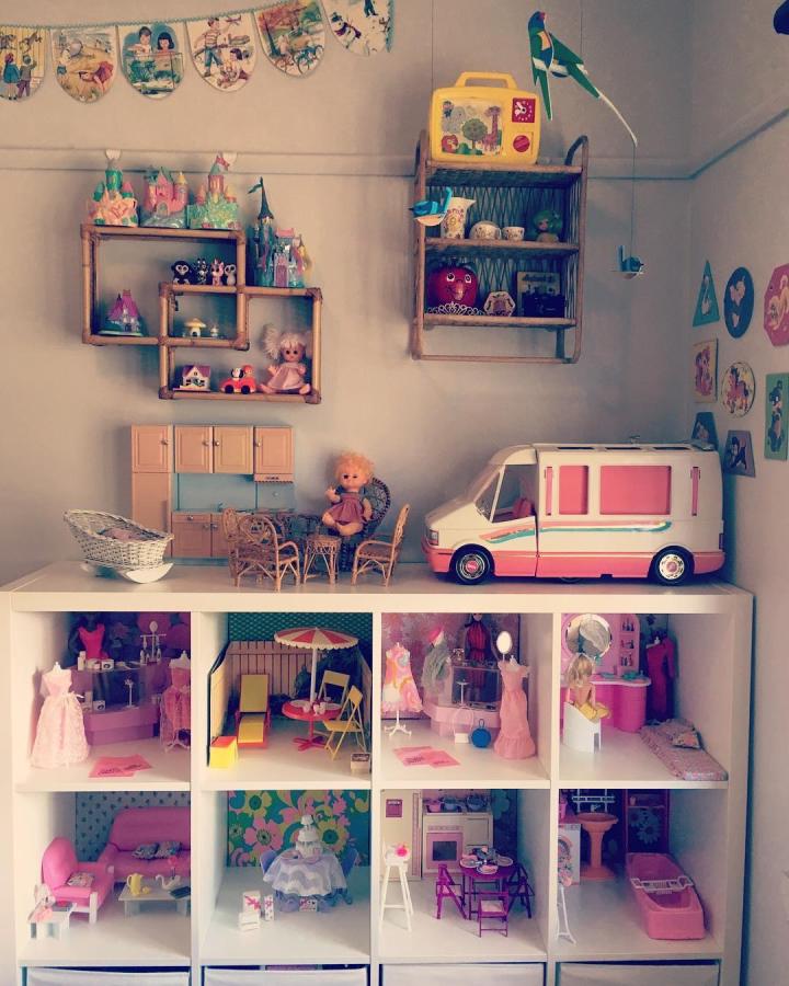 White Ikea Kallax shelf with colorful dollhouse rooms and wooden wall shelves in a playroom from @pineappleandgrape showing ikea kallax playroom hacks & ideas.