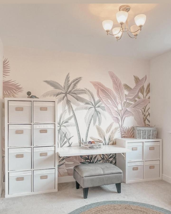 Soft pastel tropical mural with white ikea kallax playroom hacks & ideas storage units and a fold-down desk from @homeofkg.