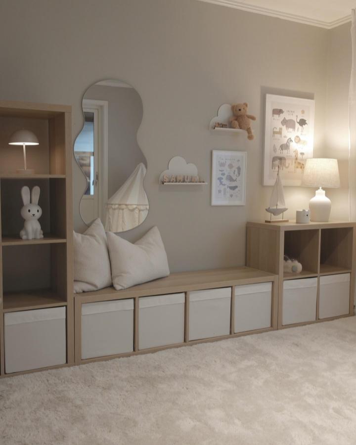 Light wood Kallax shelving with white fabric bins and soft cushions in a neutral playroom from @mariav.interior. ikea kallax playroom hacks & ideas.