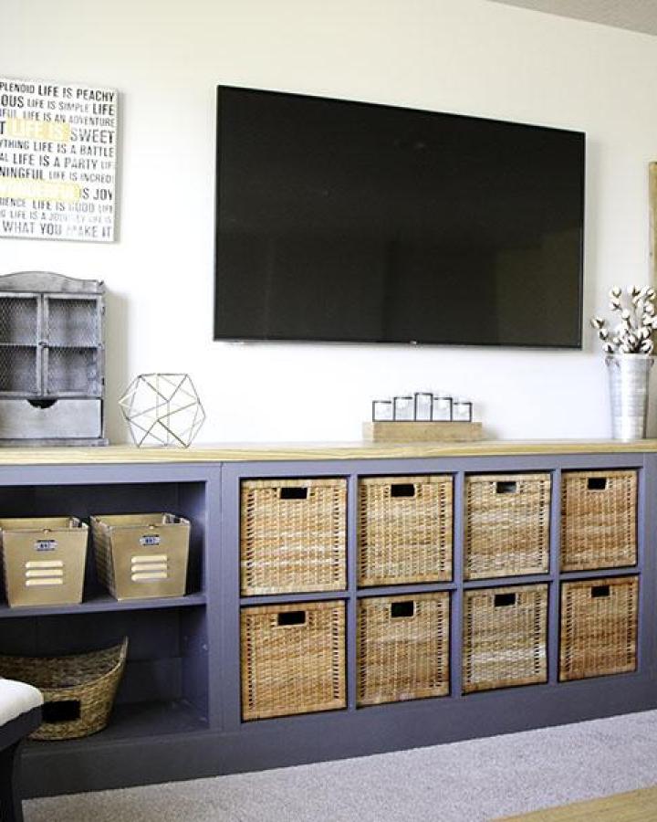 Gray painted Ikea Kallax TV unit with honey-toned woven baskets and wood top from Honeybear Lane creating a cozy media center.