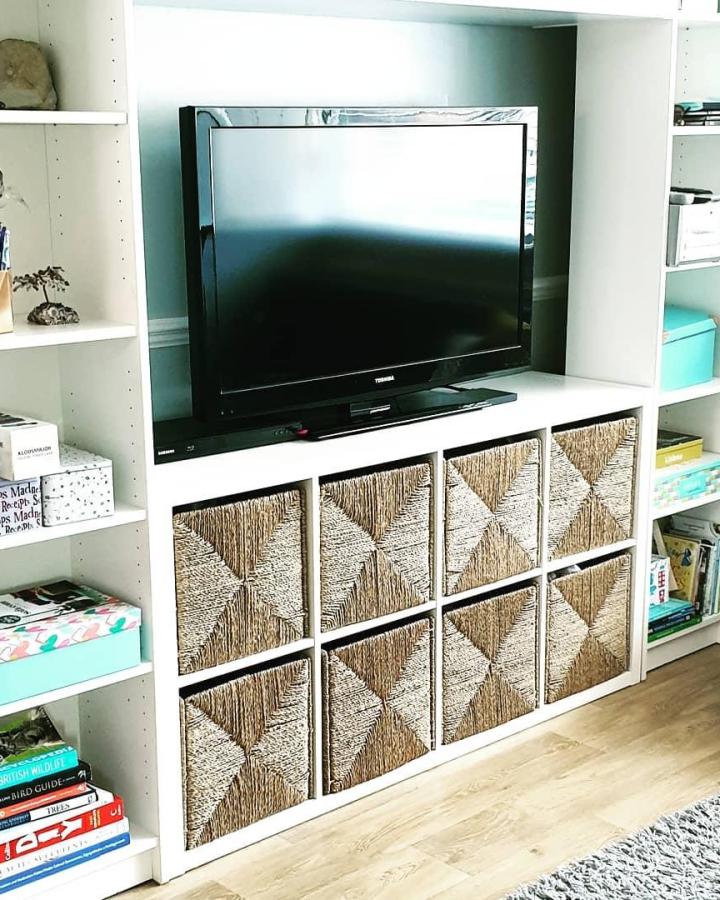 Natural woven basket inserts in white Kallax unit from @bouwerlouise. Stylish ikea kallax tv unit hacks & ideas with textured storage.