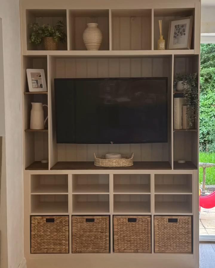 Beige painted Ikea Kallax tv unit with woven baskets and decorative ceramics from @meehanscottage creating cozy storage and display.