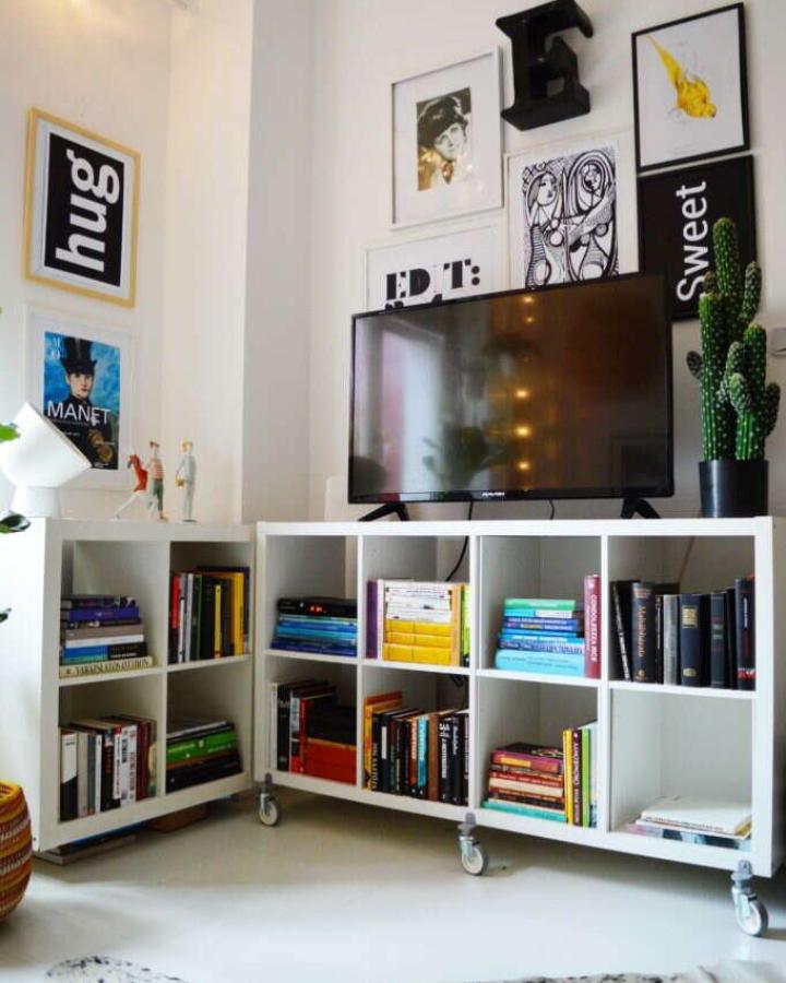 white Ikea Kallax TV unit hack with rolling casters and colorful books from @mercedes.doczi in minimalist living space