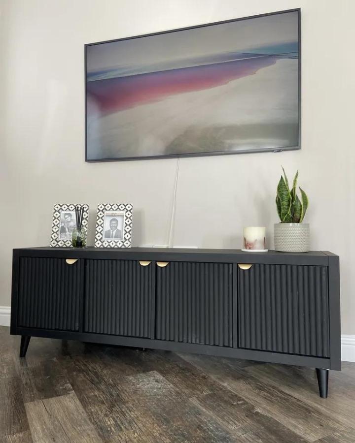 Black grooved front media cabinet with brass handles and tapered legs from Rebecca Shepherd on Real Homes in a living room setting ikea kallax tv unit hacks & ideas.