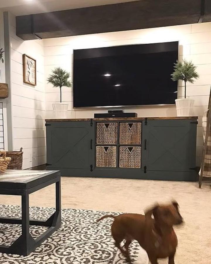 Dark green rustic ikea kallax tv unit hacks & ideas from @bloomingdiyer with barn doors and woven baskets in a cozy living room.