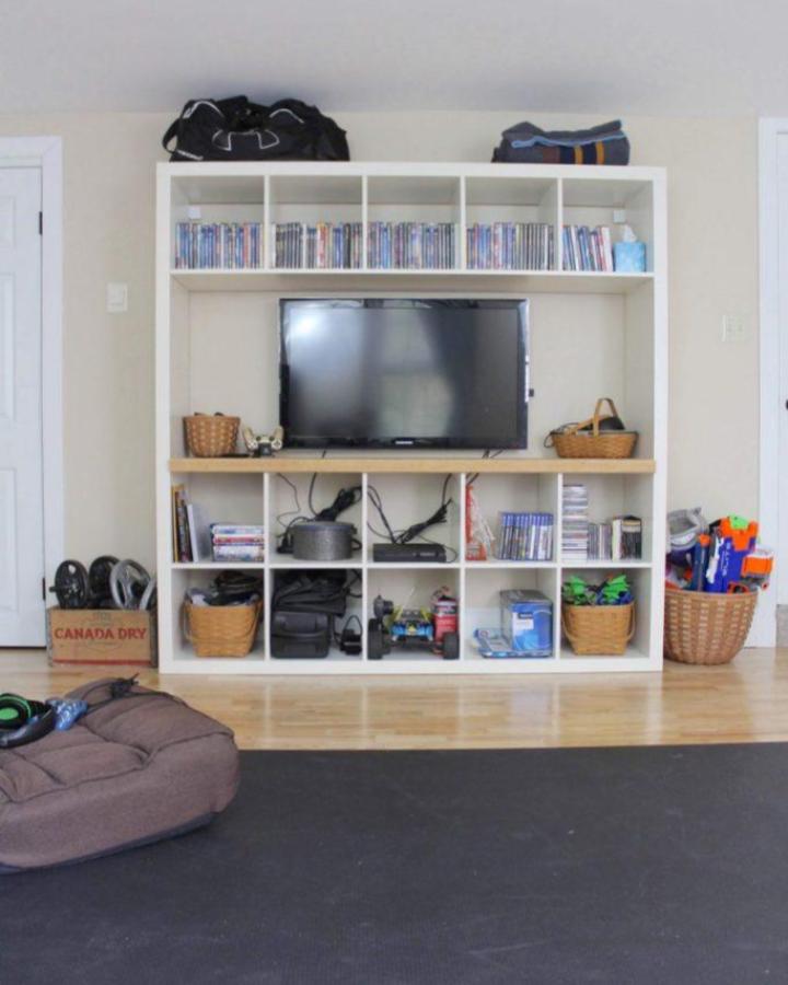 White laminate Ikea Kallax tv unit hack with wooden shelf and woven baskets from Lehman Lane. Organized mixed media storage and display.