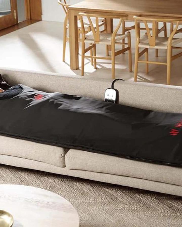 Black portable espresso machine on beige couch with dining chairs in background from Redber Coffee Roasters for valentines gift ideas for him.